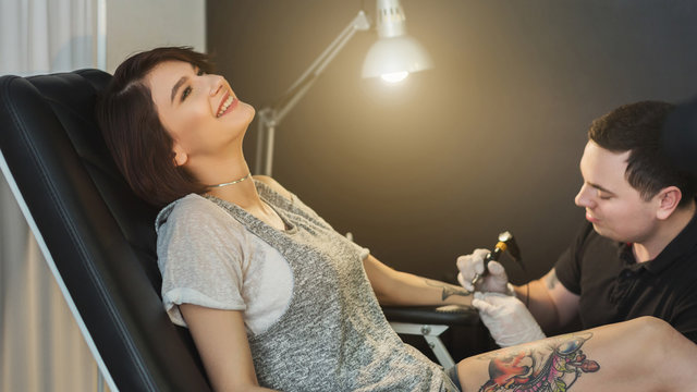 Painful body tattooing process, master working in studio