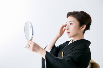 鏡を見る黒留袖の女性
