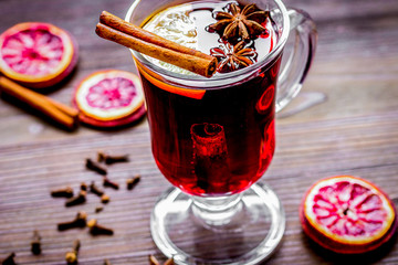 mulled wine with spices in cup on wooden background