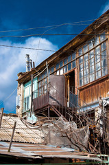 Old weathered rooftop surface of vintage authentic house with balcony veranda in courtyard of Odessa Ukraine. Traditional Odessa house with vintage rusty stairs on blue sky background. City of Odessa 