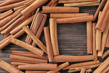 Frame made of cinnamon sticks on wooden background
