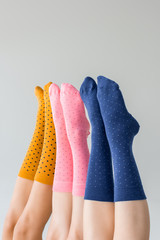 partial view of female legs in different colorful socks isolated on gray background
