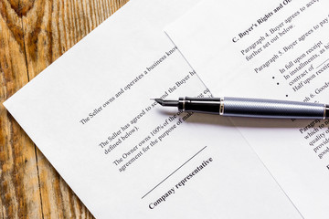 Signing the contract with pen in business work top view