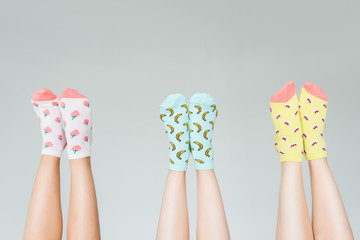 cropped image of female legs in different colorful socks isolated on gray background