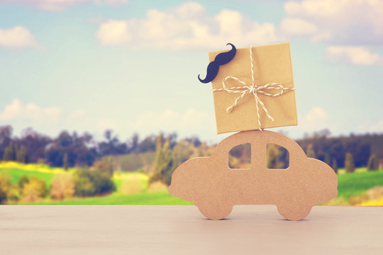 Image of wooden car with gift box on the roof, present for dad. Father's day concept.