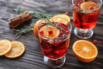 Beverage with cinnamon, orange and cranberry in glass on wooden table