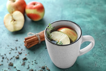 Cup of hot aromatic beverage with apple on table