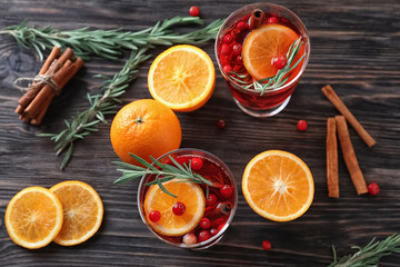 Beverage with cinnamon, orange and cranberry in glasses on wooden table