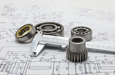 Vernier caliper lying on mechanical scheme with bearings and small gear.