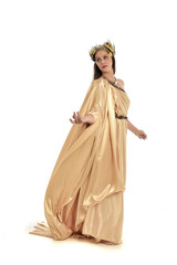 Obraz na płótnie Canvas full length portrait of brunette woman wearing long golden grecian gown, standing pose. isolated on white studio background.