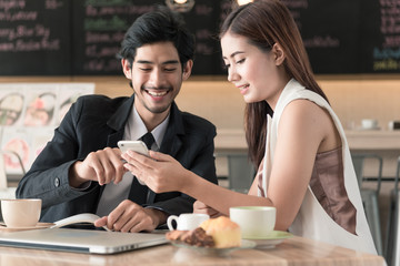 Cute couple enjoying on mobile phone together in coffee shop.