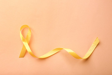 Yellow ribbon on color background. Cancer concept