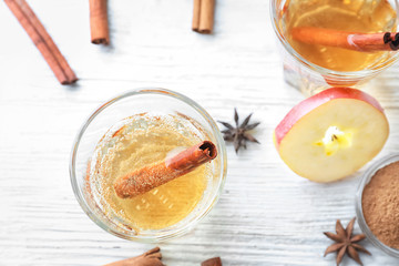 Tasty apple drink with cinnamon in glass on table