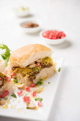 Dabeli is an Indian snack item served with Pomegranate Seeds and Cilantro in white ceramic plate. It's a popular Navratri Festival food