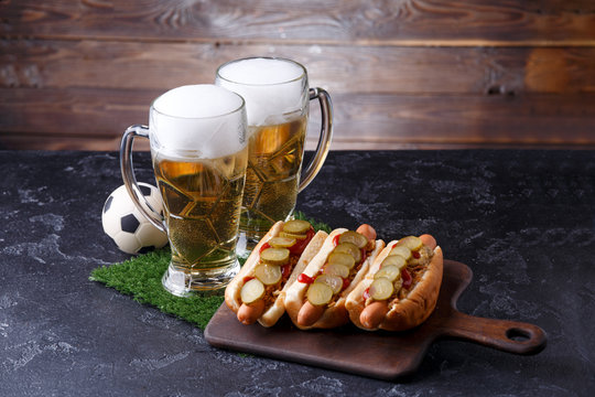 Photo of two glasses of beer, hot dogs, soccer ball