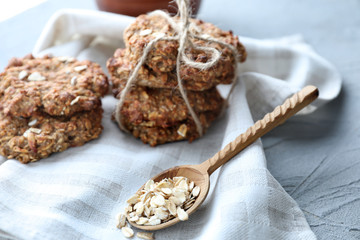 Spoon with raw oatmeal and delicious cookies on grey background