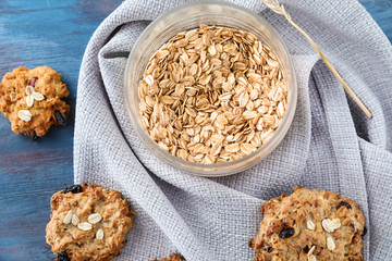 Jar with oatmeal and delicious cookies on wooden background, top view