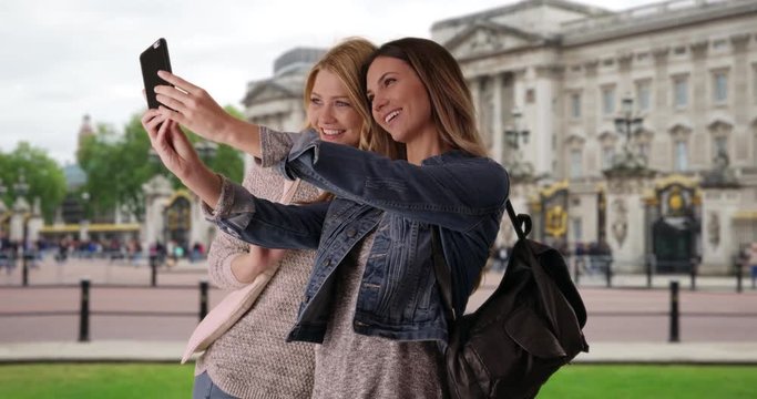 Couple of attractive white females vacationing in London take a selfie together on smartphone, Two traveling young ladies take selfie photo on phone in London, England, 4k