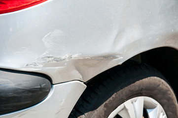 Rear side of broken and damaged silver car wreck in crash accident with scratched paint in...