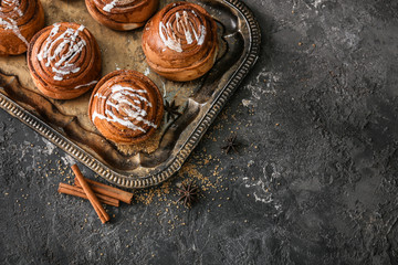 Tray with delicious cinnamon buns on dark background