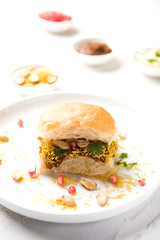 Dabeli is an Indian snack item served with Pomegranate Seeds and Cilantro in white ceramic plate. It's a popular Navratri Festival food