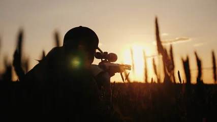Poster Im Rahmen Ein Scharfschützengewehre aus einem Gewehr mit optischem Visier. Auf dem Sonnenuntergang. Sportschießen und Jagdkonzept © StockMediaProduction