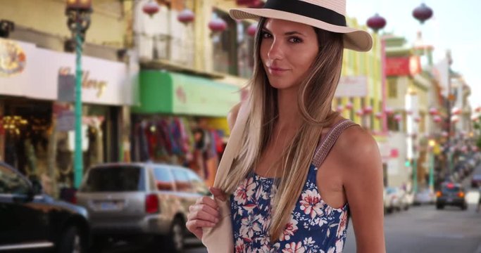 Portrait of attractive woman in summer outfit standing on Chinatown sidewalk, Stylish attractive woman in her 20s wearing fedora and romper in San Francisco Chinatown, 4k