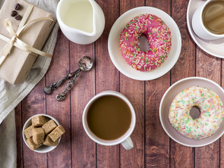 Donuts and coffee on wooden table. Top view with copy space
