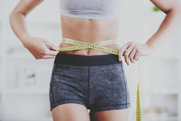 Slender girl measures waist with measuring ribbon