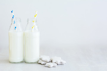Two bottles of milk and cookies shaped stars on white wooden table