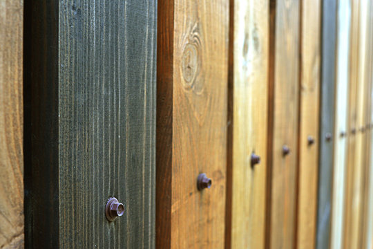 Fence as a background of multicolored wooden boards, with nails vertical texture in perspective.