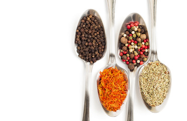 Different spices in iron spoons isolated on white