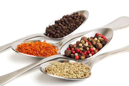 Different spices in iron spoons isolated on white