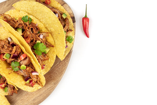 Overhead closeup photo of Mexican tacos with pulled meat, avocado, chili peppers, cilantro, with copy space, on white
