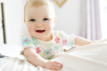 Fototapeta premium Baby girl in white bedding at home look nice