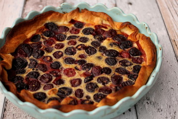 Fresh homemade cherry tart in blue baking pan on wooden table