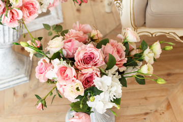 A large bouquet of bright pink flowers stands on a wooden floor in a bright white room in baroque style. Daylight, close-up, selective focus, nobody, objects