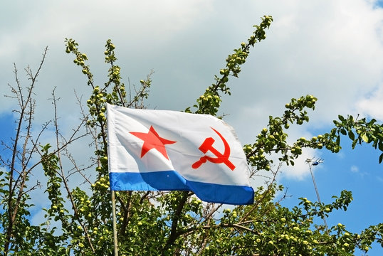 Old Naval flag of the USSR, july apple tree on background. Russian navy day concept.
