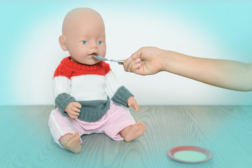 The child is feeding the doll.