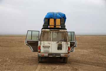 samochód terenowy z bagażami na dachu stojący na pustkowiu
