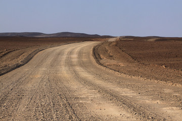 Fototapeta na wymiar szeroka szutrowa droga przez piaszczyste pustkowie
