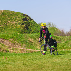 Fototapeta na wymiar Sporty woman cyclist riding bike on green grass