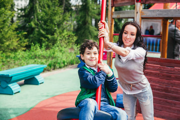 Fototapeta na wymiar emotional funny little boy and mother in the amusement park. children outdoors. vacation in the summer park