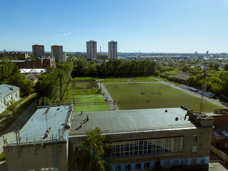 Football field without fans with a small number of players, green grass in Russia. Aerial view.