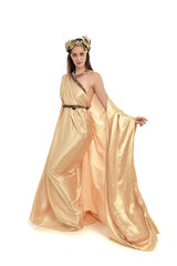 Fototapeta premium full length portrait of brunette woman wearing long golden grecian gown, standing pose. isolated on white studio background.