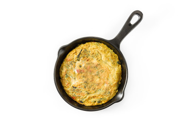 Frittata made of eggs and vegetables in a iron pan, isolated on white background. Top view
