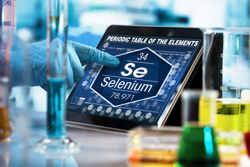 researcher consulting on the digital tablet data of the chemical element Selenium Se / scientist...