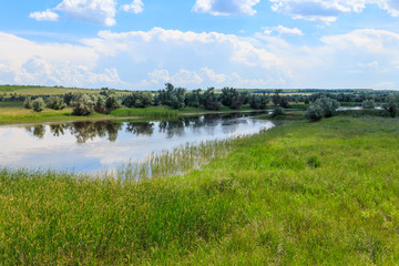 Summer landscape with small river and blue cloudy sky