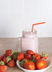 Healthy strawberry cocktail on a wooden background with ripe berries on a plate