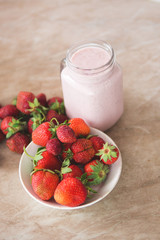 Healthy strawberry cocktail on a wooden background with ripe berries on a plate